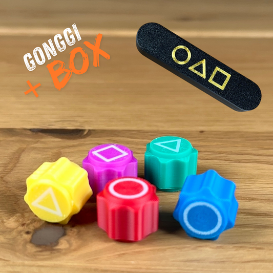 Mehrere Gonggi-Würfel aus PLA, gefüllt mit Stahlkugeln, auf einer Spielfläche